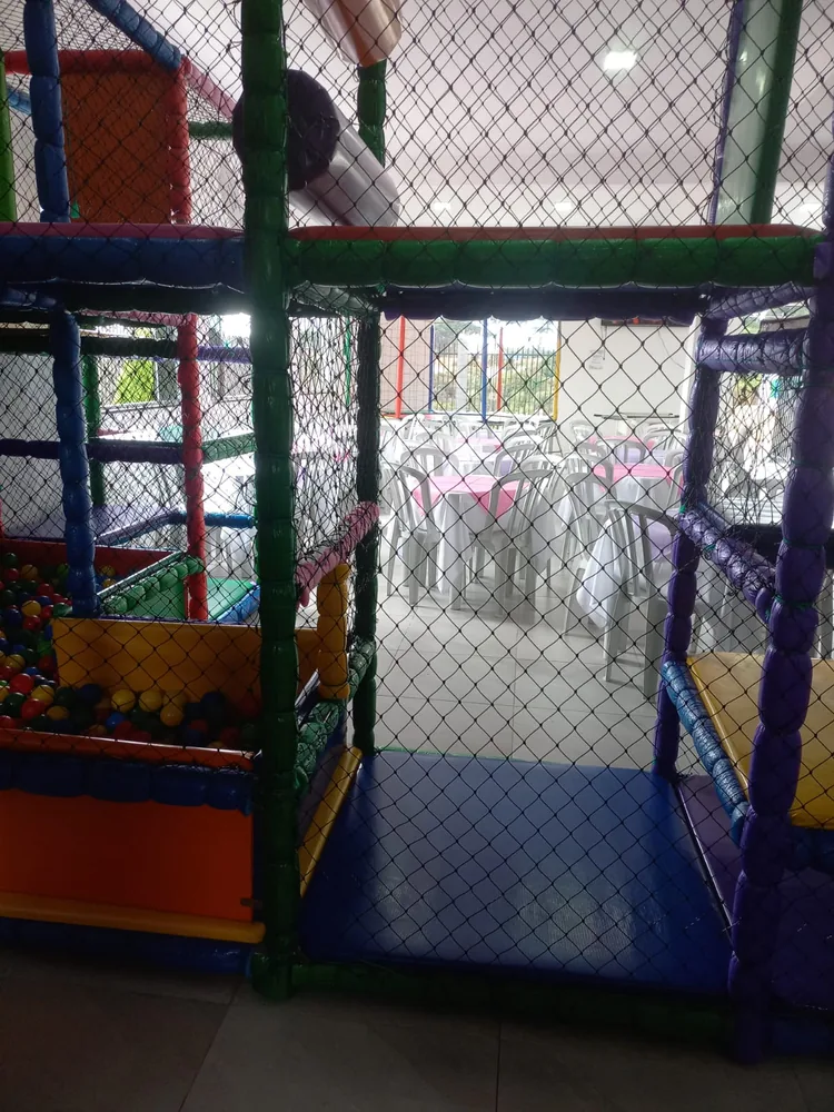 Playground colorido com redes, piscina de bolinhas e escorregador dentro do salão
